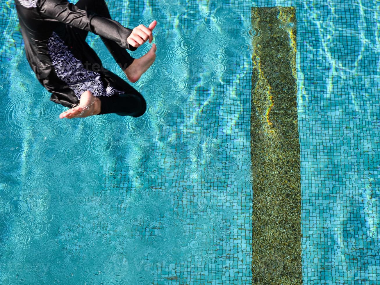 High Level View ein Mädchen, das an einem sonnigen Tag in den Pool springt foto