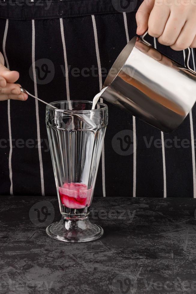 Nahaufnahme eines Baristas, der Kaffee mit Sirup und Sahneschaum im Café zubereitet foto