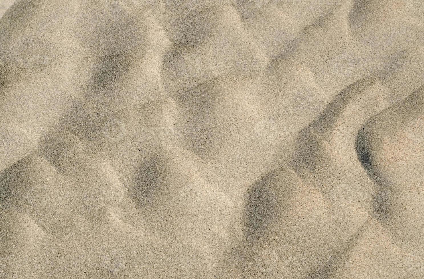 welliger Wüstensand-Texturhintergrund. gelber feiner strandsand. texturhintergrund aus goldenem sand, sommersonnenferienkonzept. die Textur des Strandsandes als Hintergrund. foto