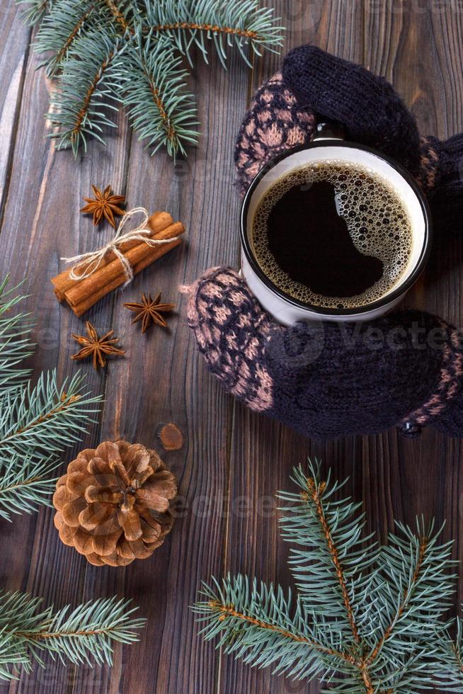 weibliche hände, die becher heißen schokoladenkaffees auf rustikalem hölzernem hintergrund mit weihnachts-tannenbaumzweig, kopienraum halten. Konzept für heiße Getränke im Winter foto