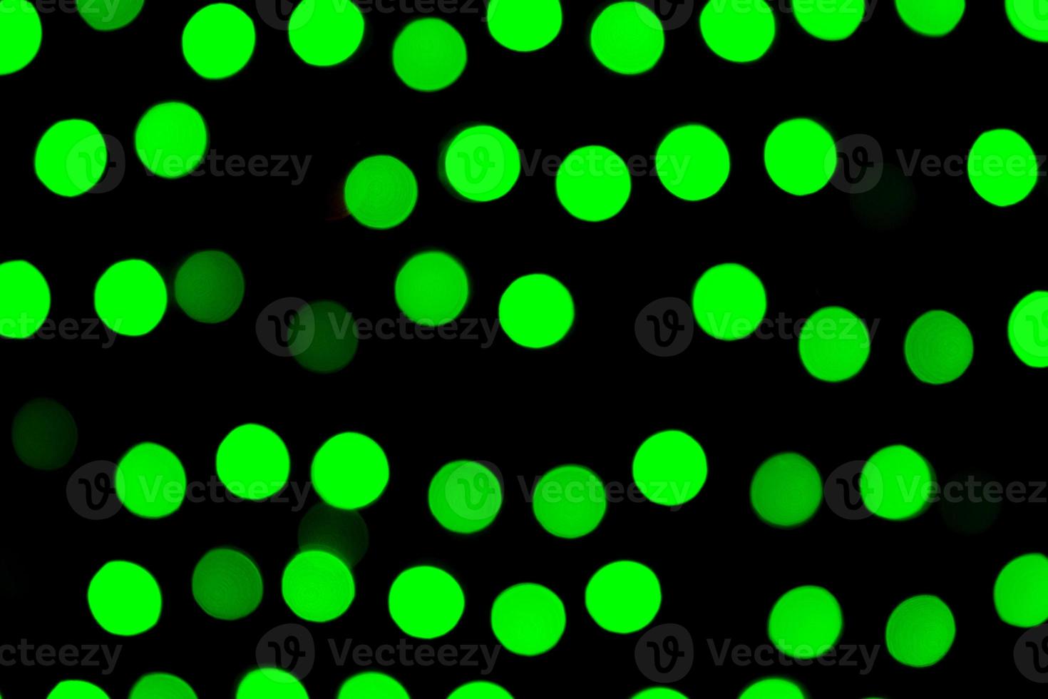 Unfokussiertes abstraktes grünes Bokeh auf schwarzem Hintergrund. defokussiert und verschwommen viele runde licht foto