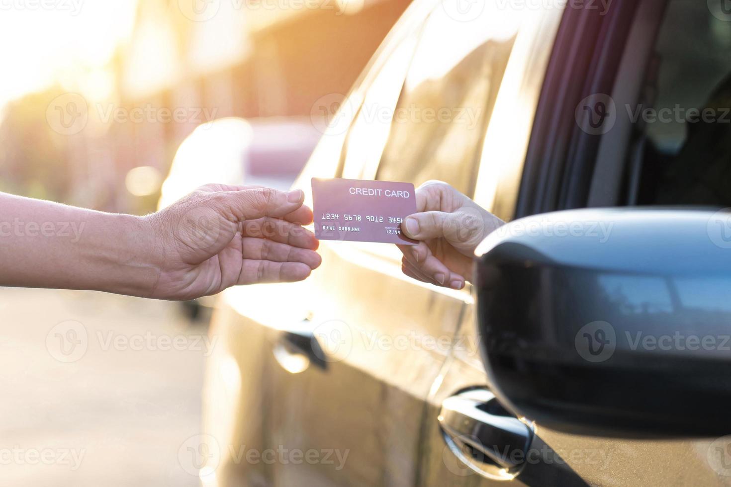 frauen geben männern kreditkarten, wenn sie für einkäufe bezahlen, und fahren ihr ein auto, durchfahrtskaufkonzept foto