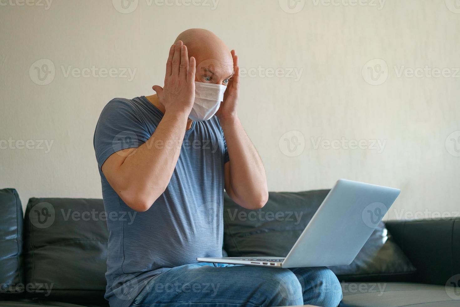 ein glatzköpfiger erwachsener mann kommuniziert auf einem laptop zu hause auf der couch, zeigt eine handgeste. das konzept der kommunikation in der quarantäne foto