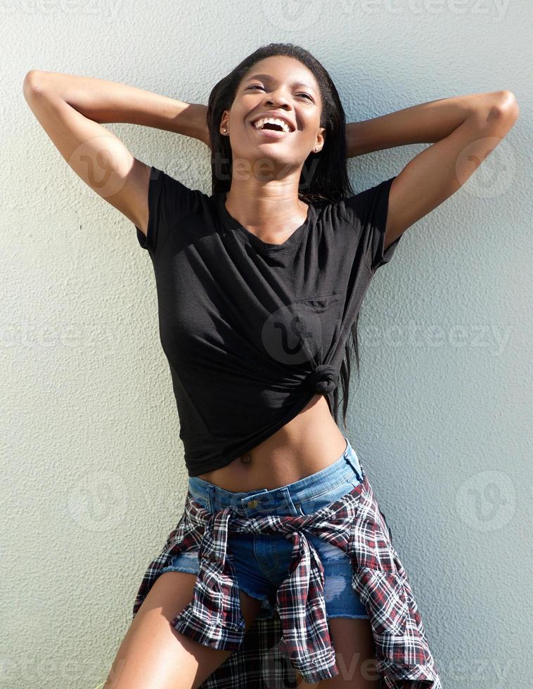 junge afrikanische Frau, die mit Händen hinter Kopf lächelt foto