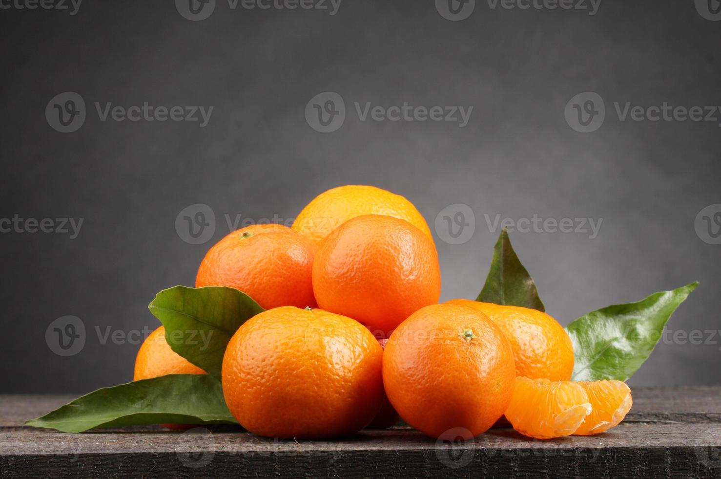 Mandarinen mit Blättern auf Holztisch auf grauem Hintergrund foto