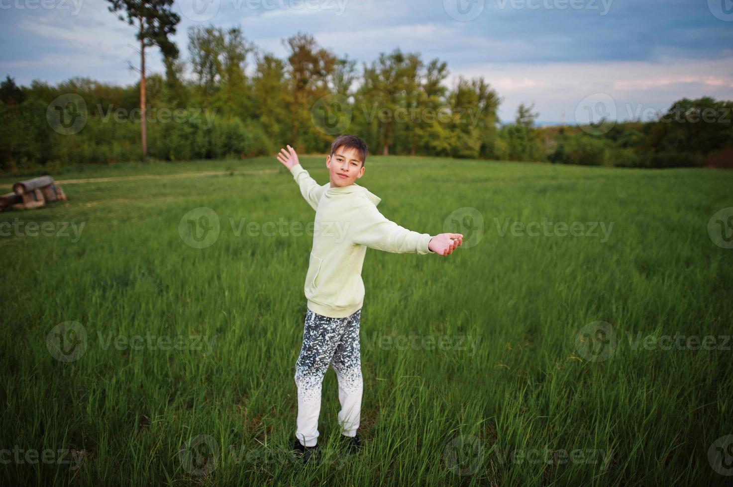 Junge hat Spaß auf der Wiese. Teenager stehen im grünen Gras. foto