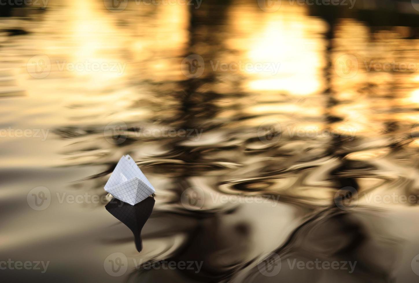 Ein Papierboot schwimmt bei einem wunderschönen Sonnenuntergang auf den Wellen im Wasser. Origami-Schiff segelt. das Konzept eines Traums, Zukunft, Kindheit, Freiheit oder Hoffnung. foto