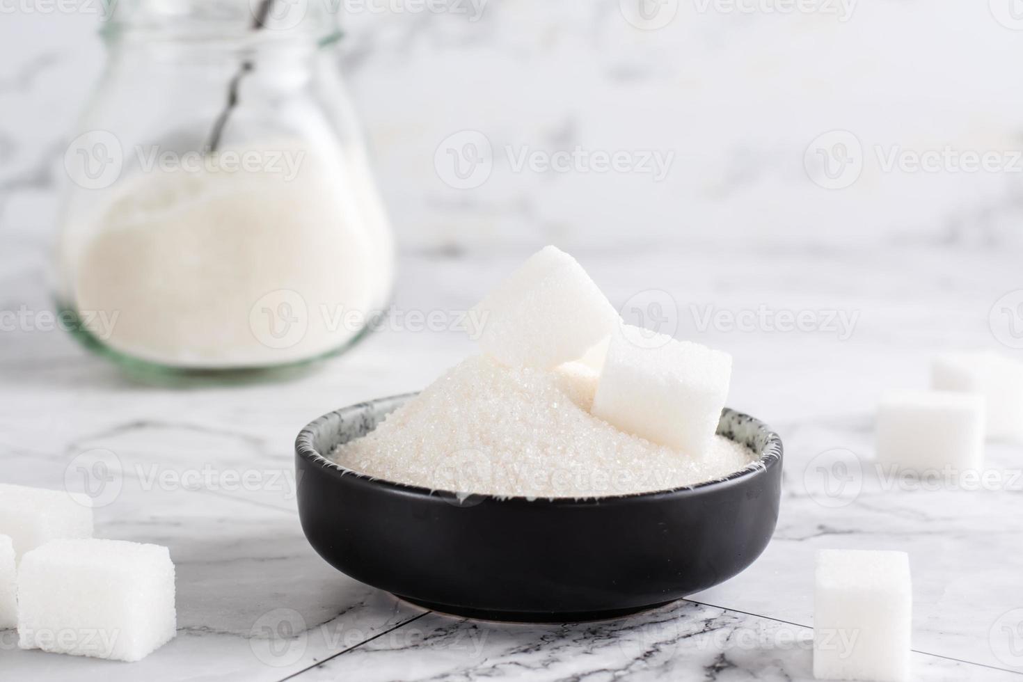 Kristallzucker und Würfelzucker in einer Schüssel und Zucker in einem Glas auf dem Tisch. foto