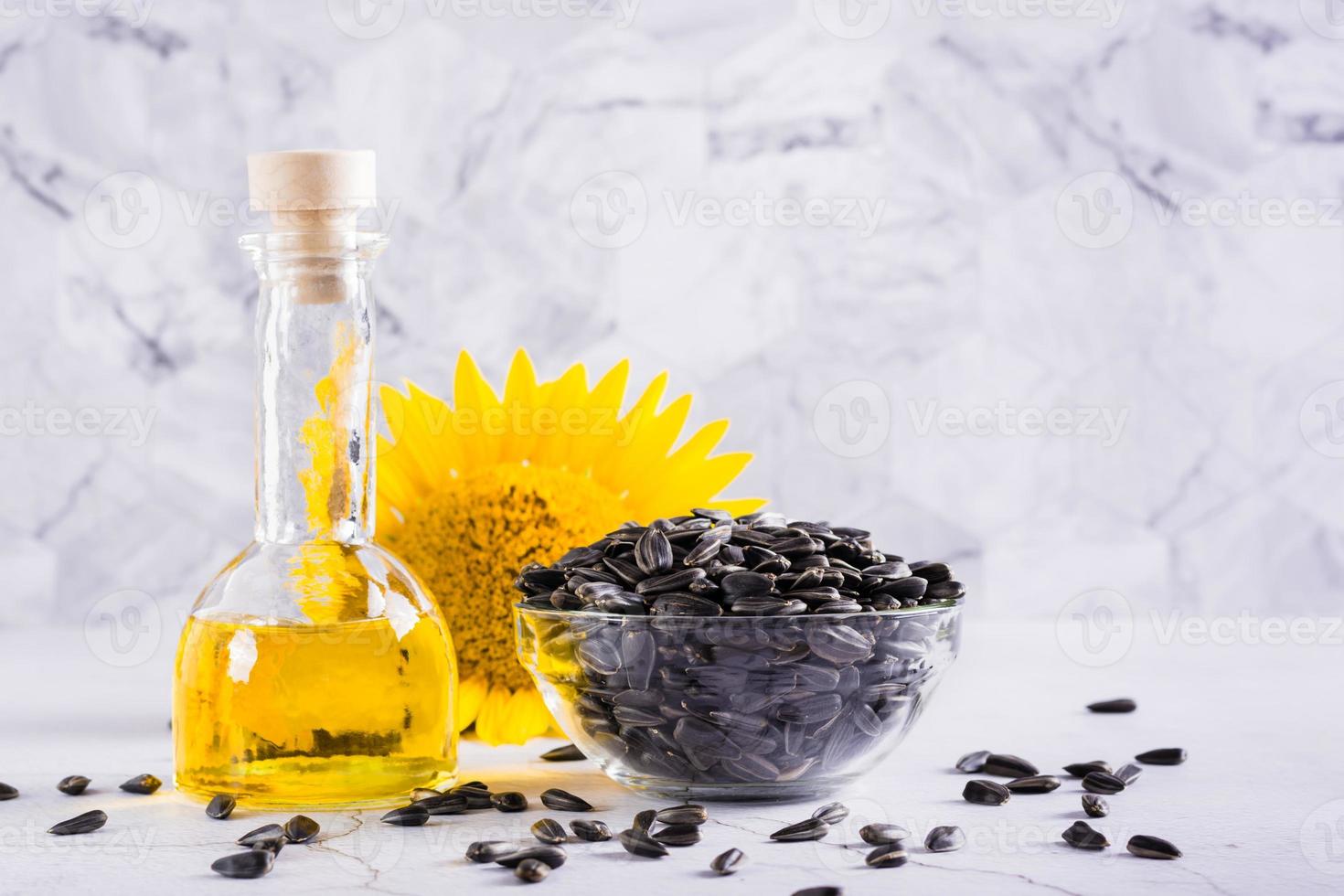 Sonnenblumenöl in einer Flasche und Samen in einer Schüssel auf dem Tisch. Ernte und natürliche Ernährung foto