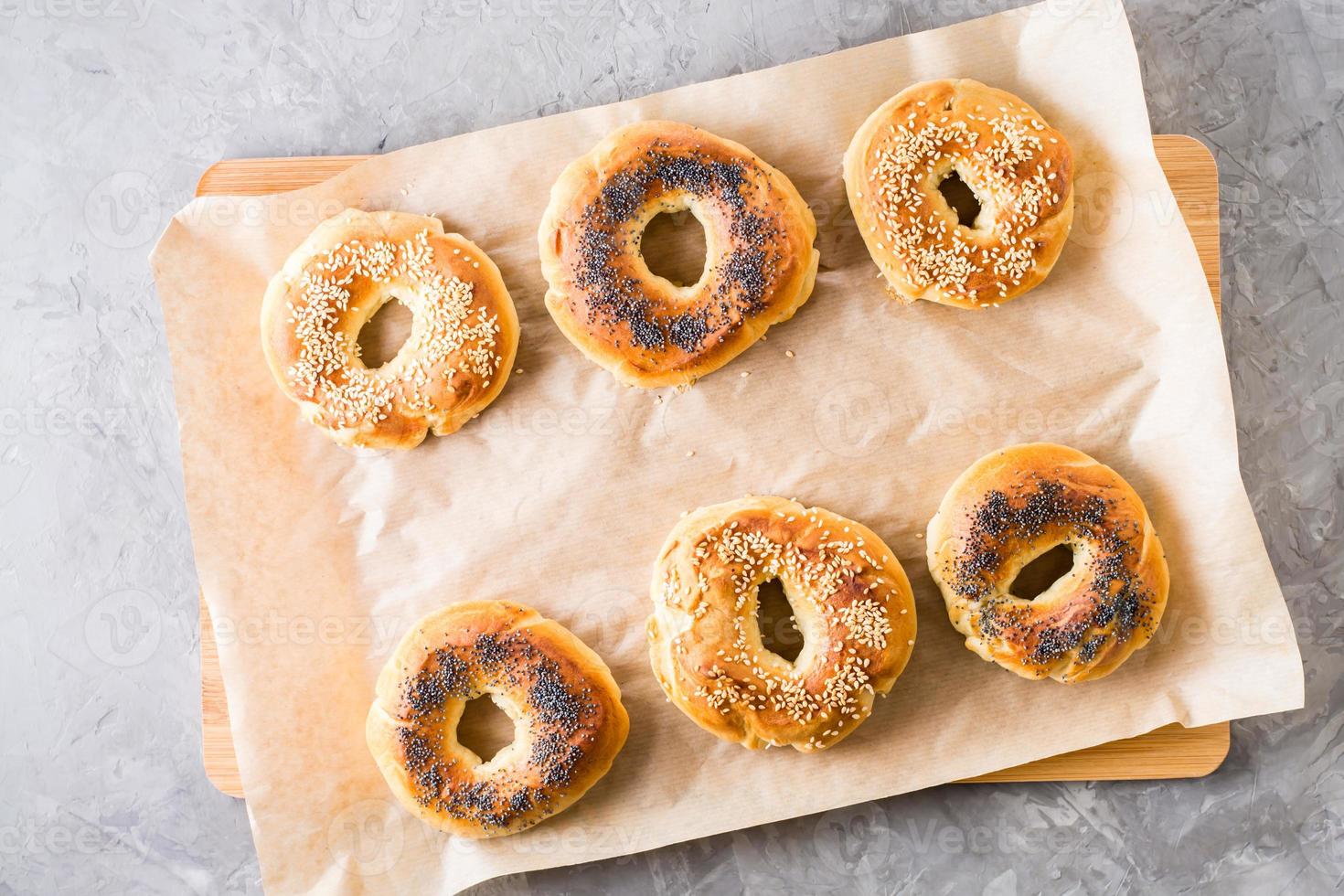 gebackene Bagels mit Mohn und Sesam auf Pergament. hausgemachtes Gebäck. Ansicht von oben foto