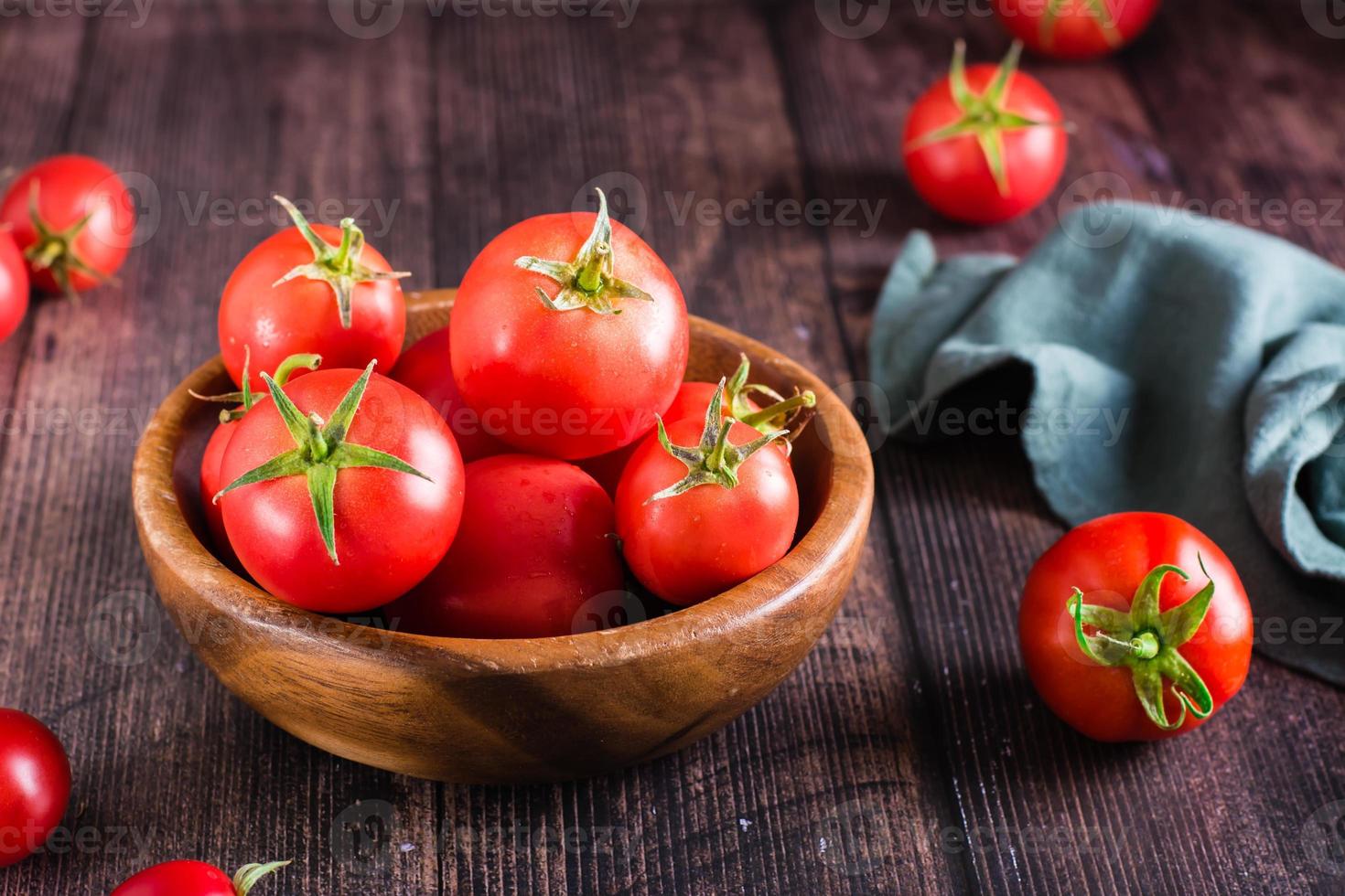 Reife rohe ganze Tomaten in einer Schüssel auf einem Holztisch. lokale Produkte ernten. foto