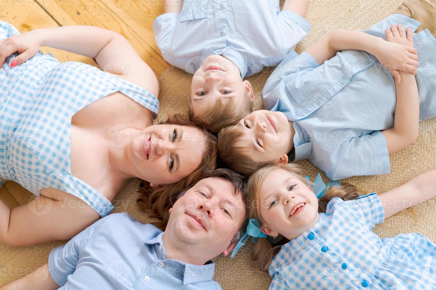 porträt glückliche kaukasische familie, die auf dem bodenhaus posiert und auf dem teppich liegt foto