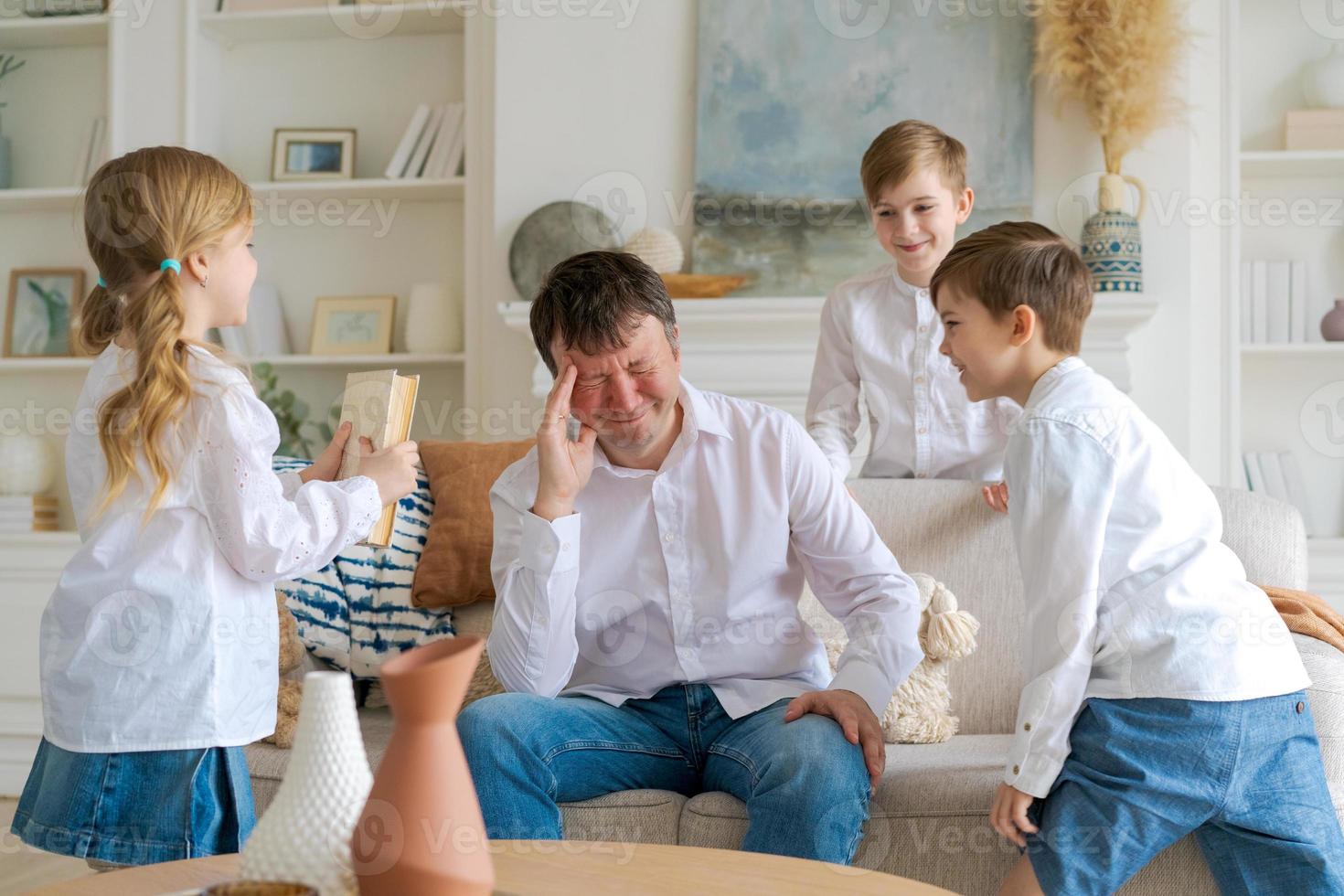 Ein verärgerter Vater sitzt zu Hause im Wohnzimmer auf dem Sofa und ist vom Lärm abgelenkt foto