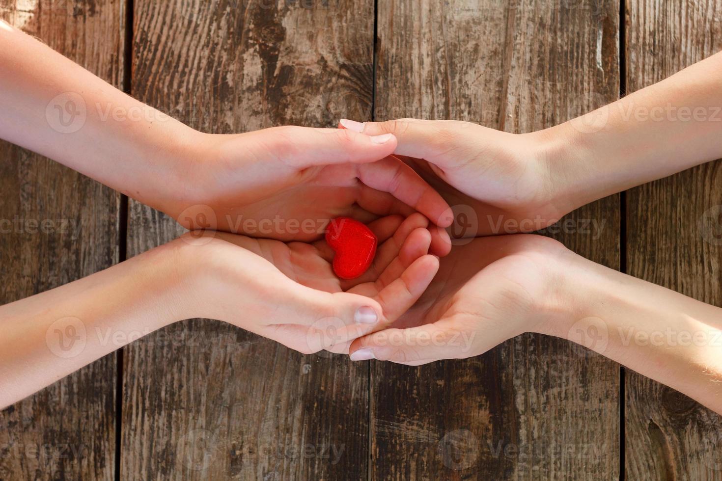 kleines rotes herz liegt in den händen von männern und frauen, das konzept von liebe und romantik foto