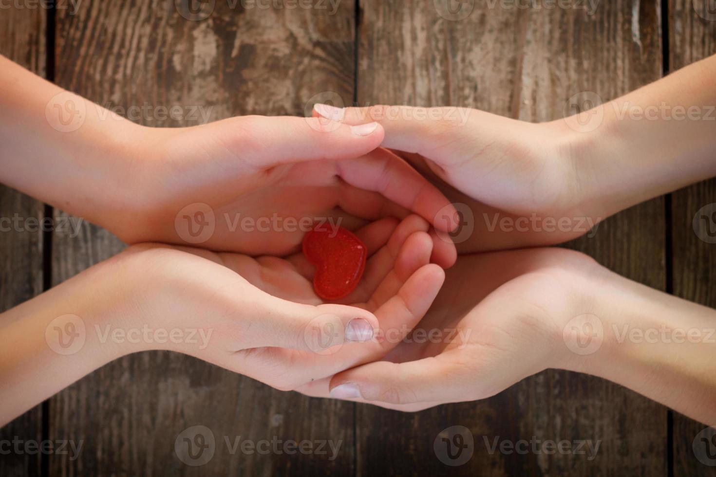 kleines rotes herz liegt in den händen von männern und frauen, das konzept von liebe und romantik foto