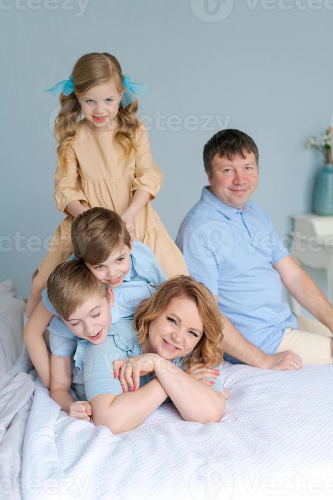 fröhliche familie, die zusammen auf dem bett spielt. Eltern verbringen ihre Freizeit foto