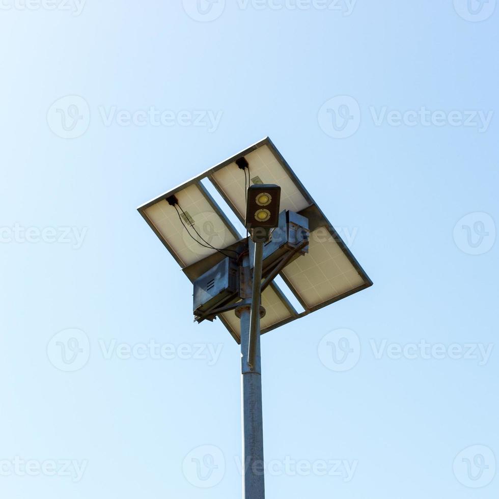 Straßenlaterne mit kleinem Solarpanel auf blauem Himmelshintergrund foto