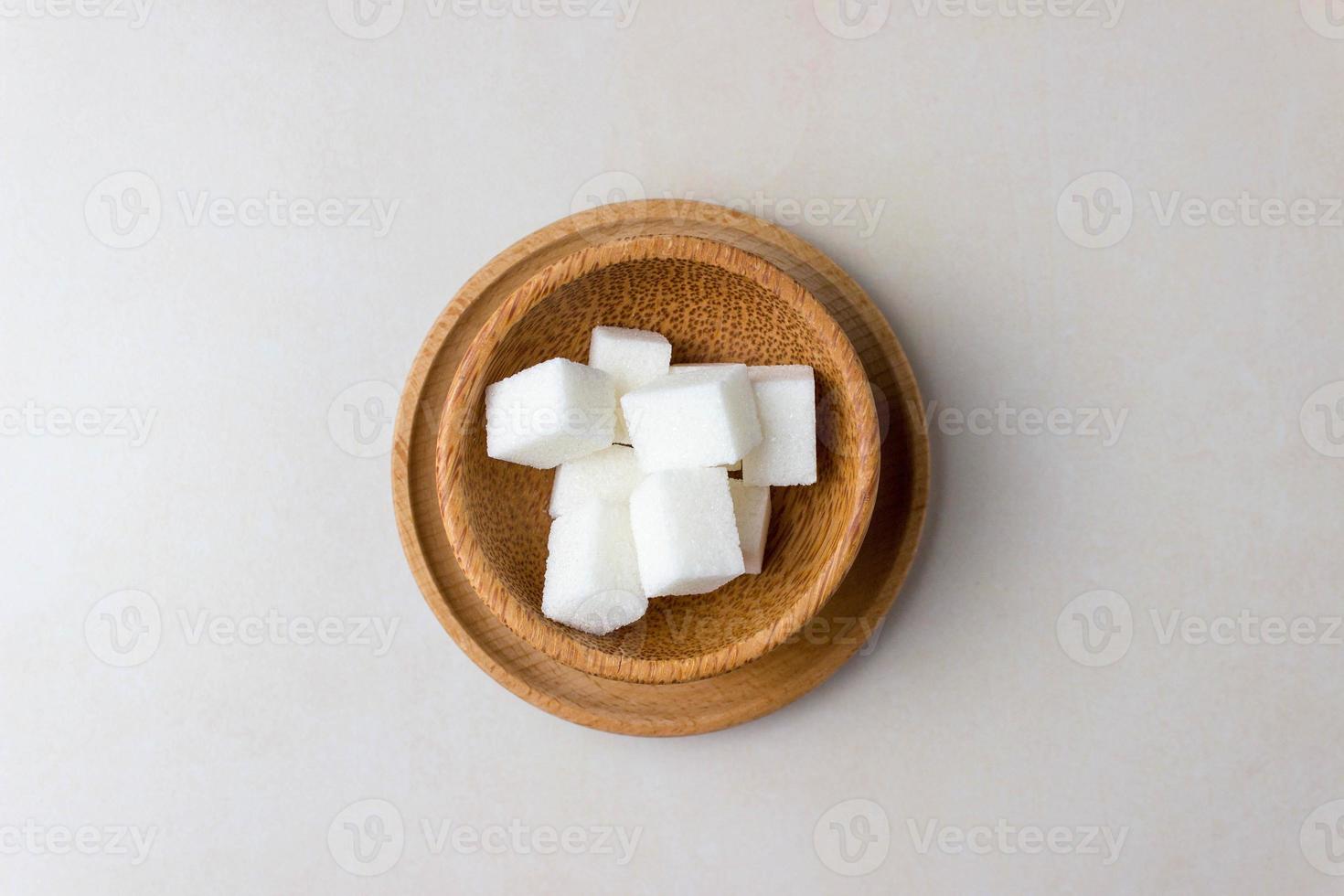 Zuckerwürfel in einem Holzteller in der Mitte des Küchentisches. Ansicht von oben foto