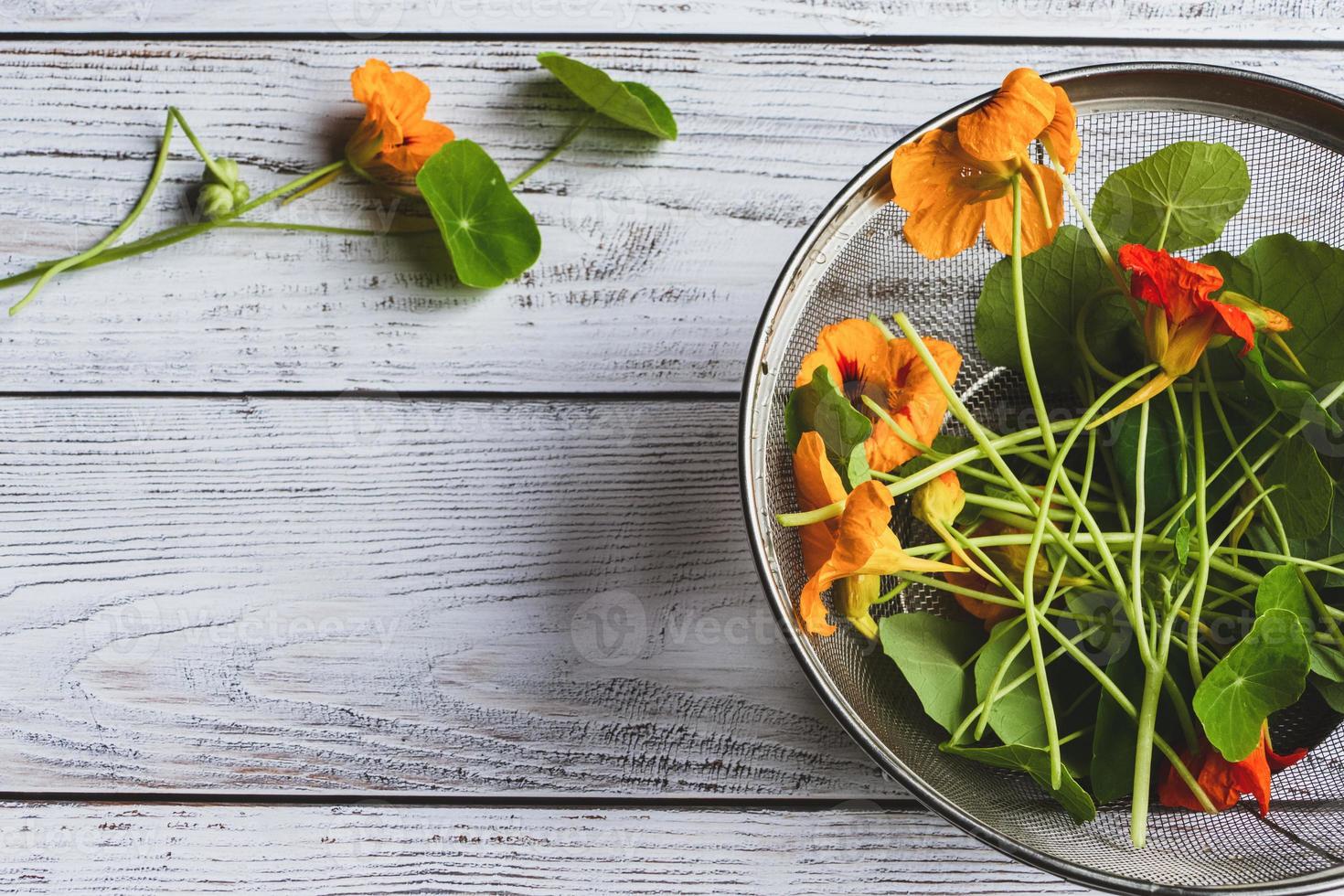 Kapuzinerkresse-Pflanzen, Mönchskresse-Blumen und -Blätter, die zum Kochen auf dem Küchentisch zubereitet werden, Draufsicht foto