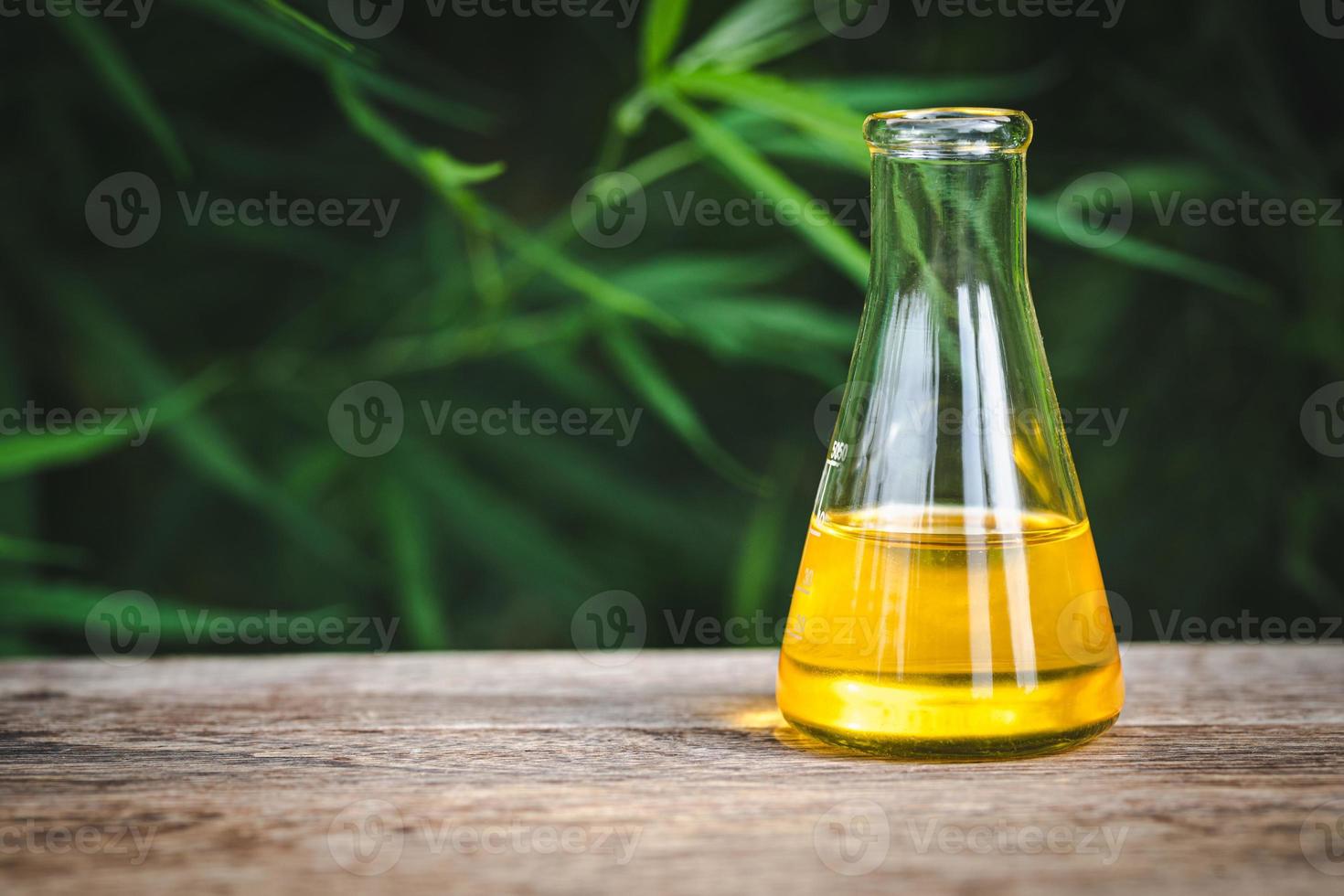 cbd-hanföl, marihuanapflanze und cannabisöl auf holztisch, medizinisches marihuanaölkonzept foto
