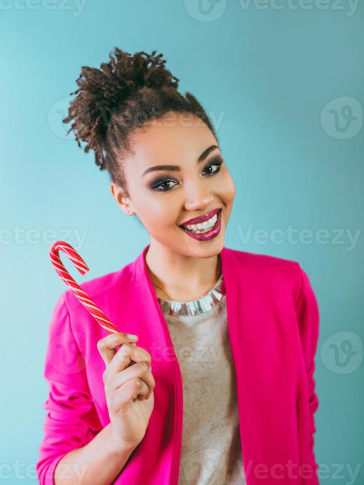 fröhliche und glückliche afroamerikanische Frau mit Zuckerstange. Weihnachten, Neujahr, Zucker, Glück, Ferienkonzept foto