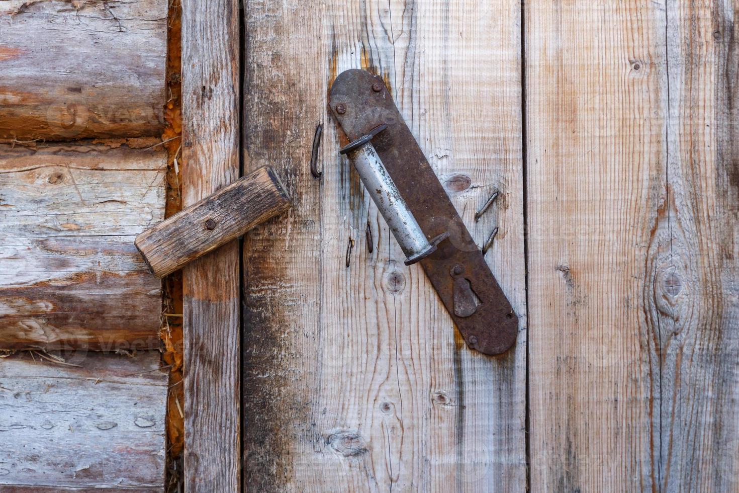 Eisengriff an einer Holzwand. Die Tür wird mit einem Holzriegel geschlossen. foto