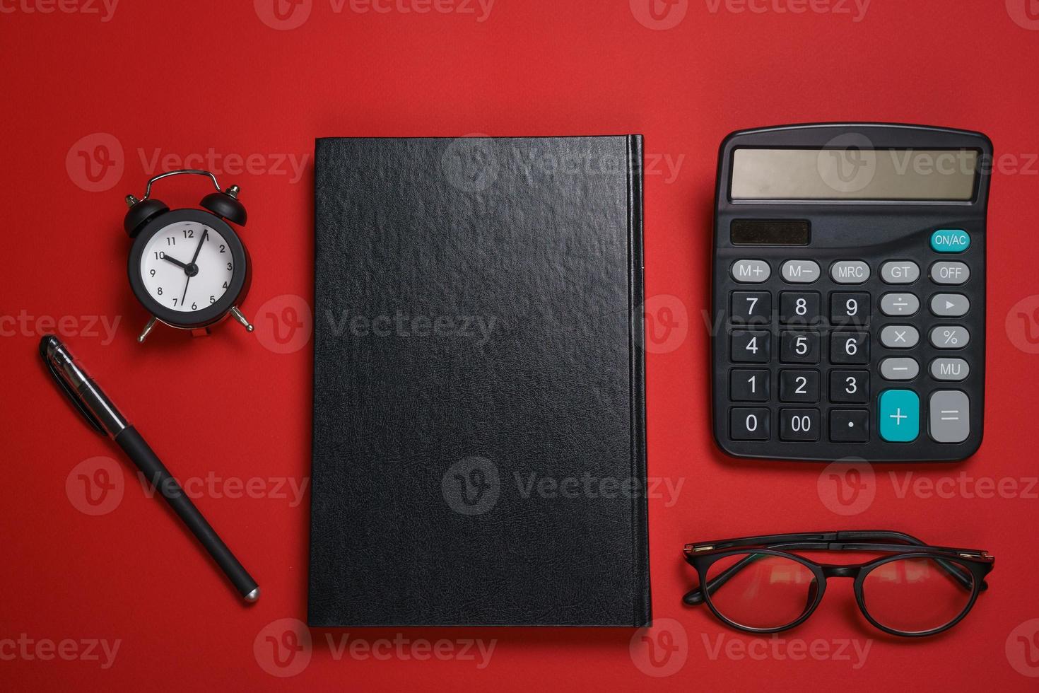 männlicher schwarzer Notizblock Kugelschreiber und Taschenrechner, kleiner Wecker und Brille foto