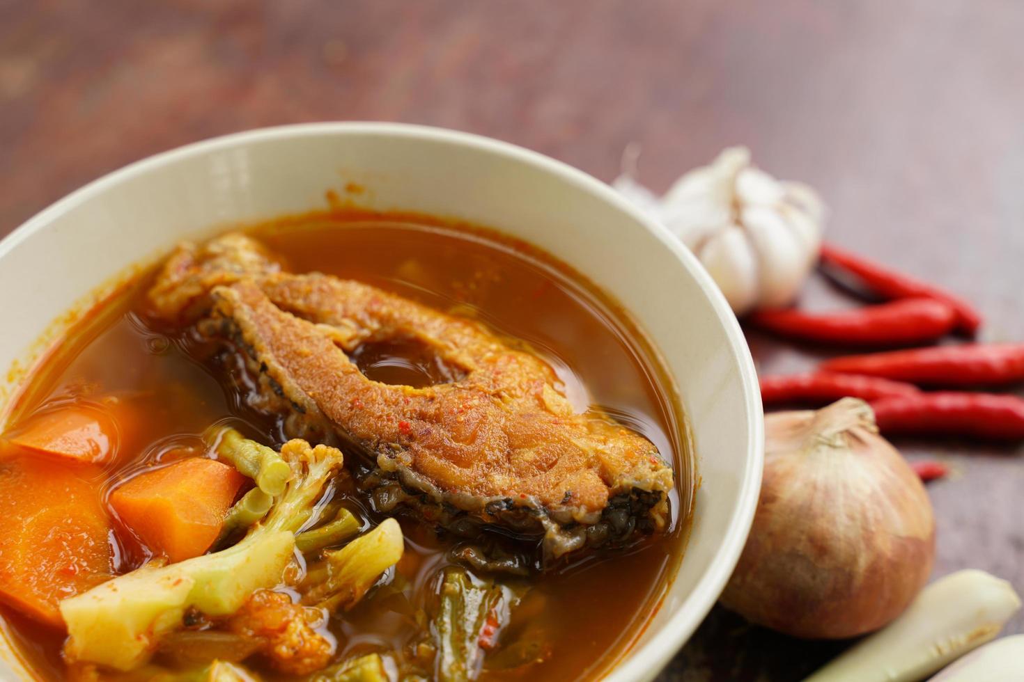 Tamarinden-Curry mit gebratenem Fisch und Gemüse auf Holzboden - thailändische Art, die köstlich ist und sehr beliebt ist. foto