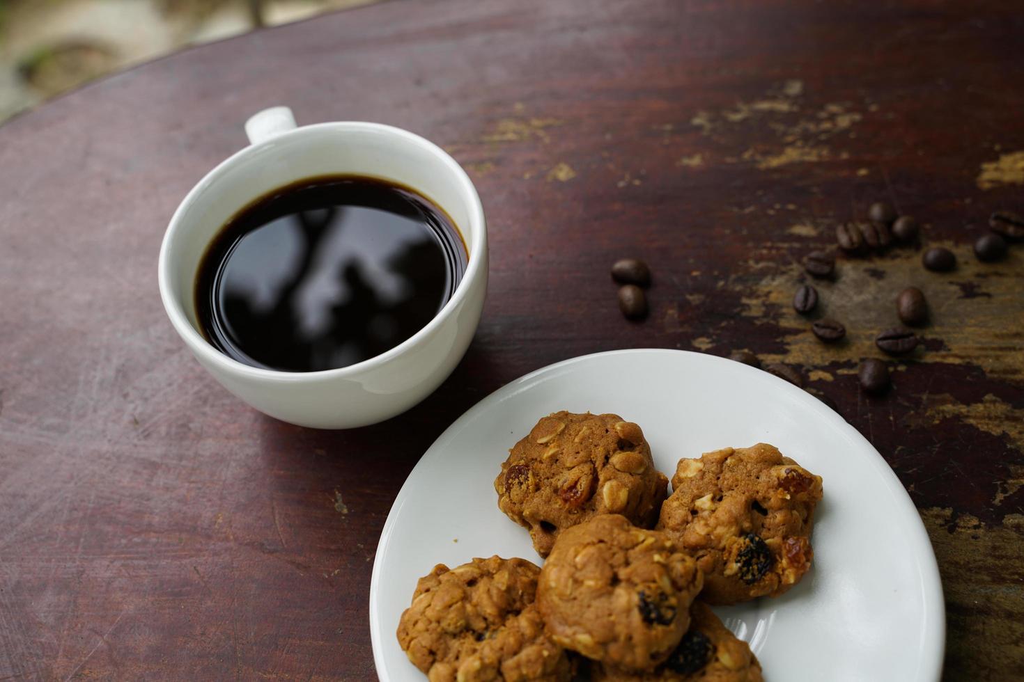 schwarze kaffeetasse mit keksen auf holzboden, schwarzer kaffee am morgen mit keksen zu trinken. foto