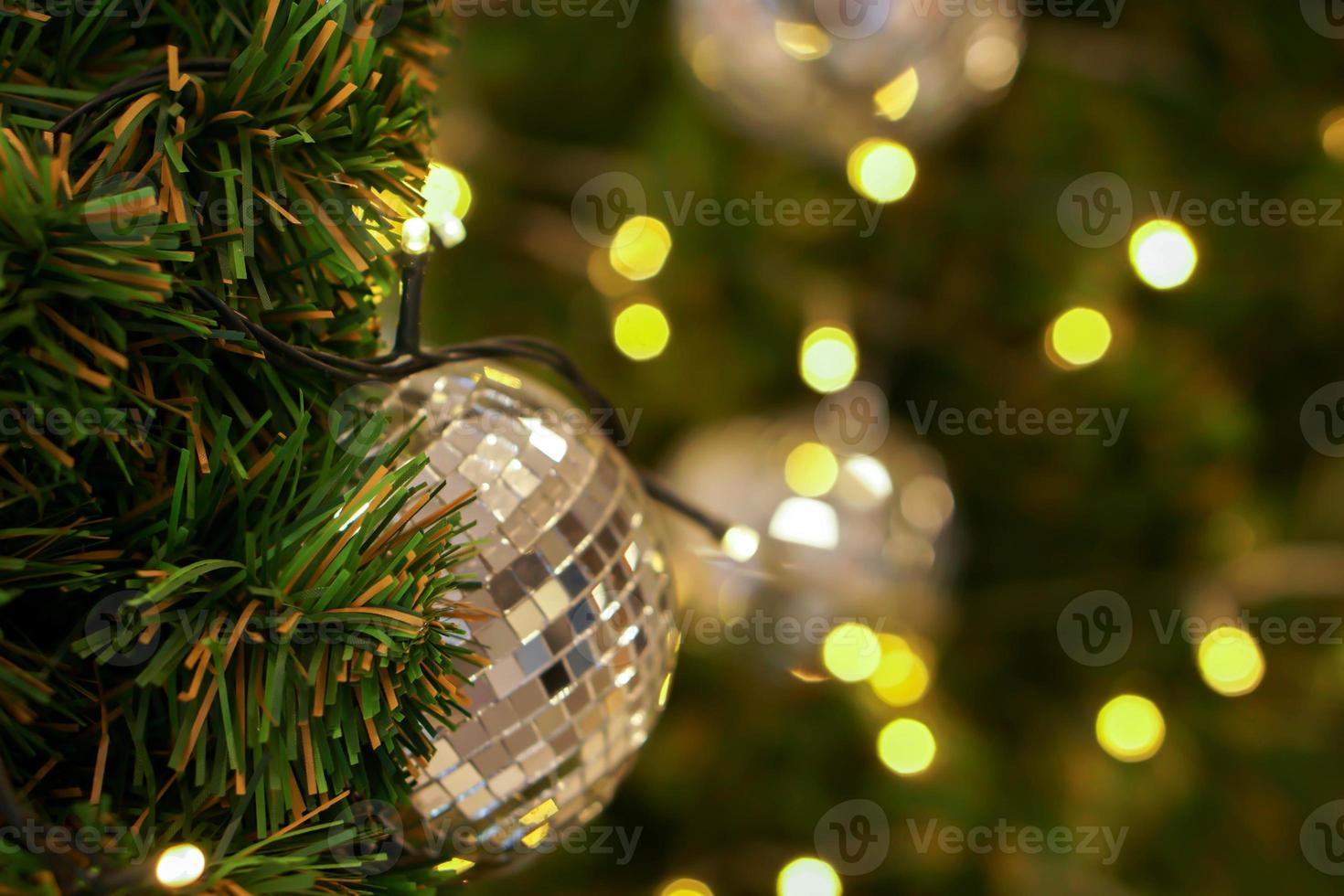 Kristallkugel auf Kiefer am Weihnachtstag mit verschwommenem Hintergrund und Bokeh der Weihnachtsbeleuchtung dekoriert. foto