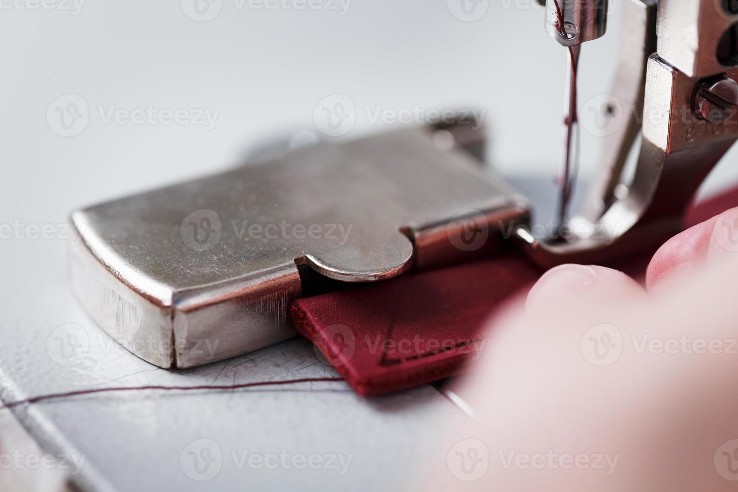 die Hände eines Meisters und die Nadel eines Lederprodukts, das auf einer Nähmaschine näht. Handarbeit, Geschäft. foto