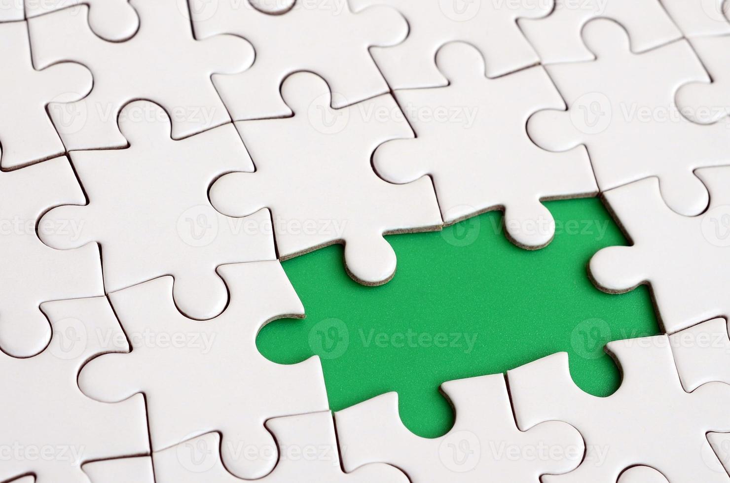 Nahaufnahmetextur eines weißen Puzzles im zusammengebauten Zustand mit fehlenden Elementen, die einen grünen Block für Text bilden. Platz kopieren foto