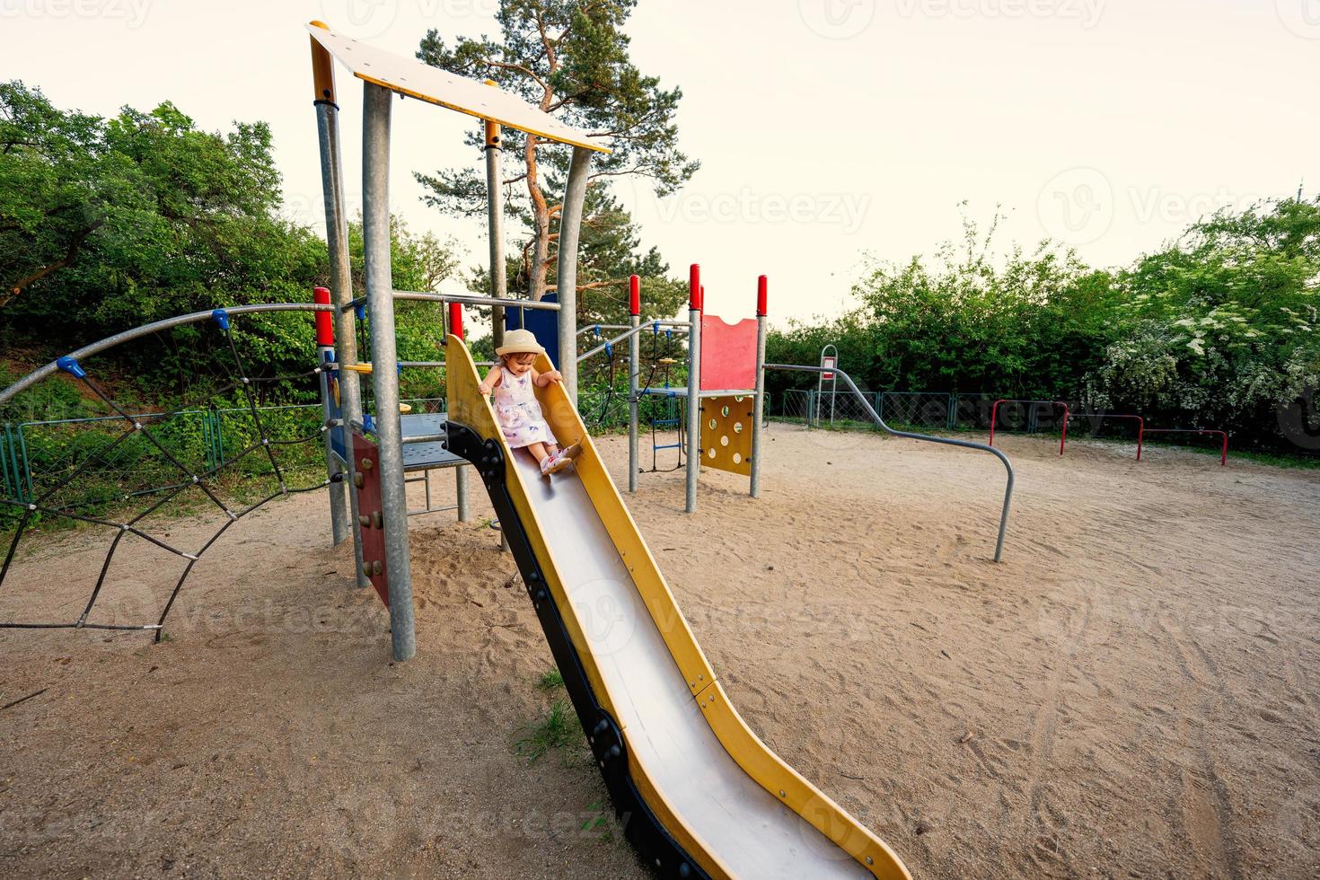 baby mädchen rutscht im kinderspielplatz spielzeug im öffentlichen park. foto