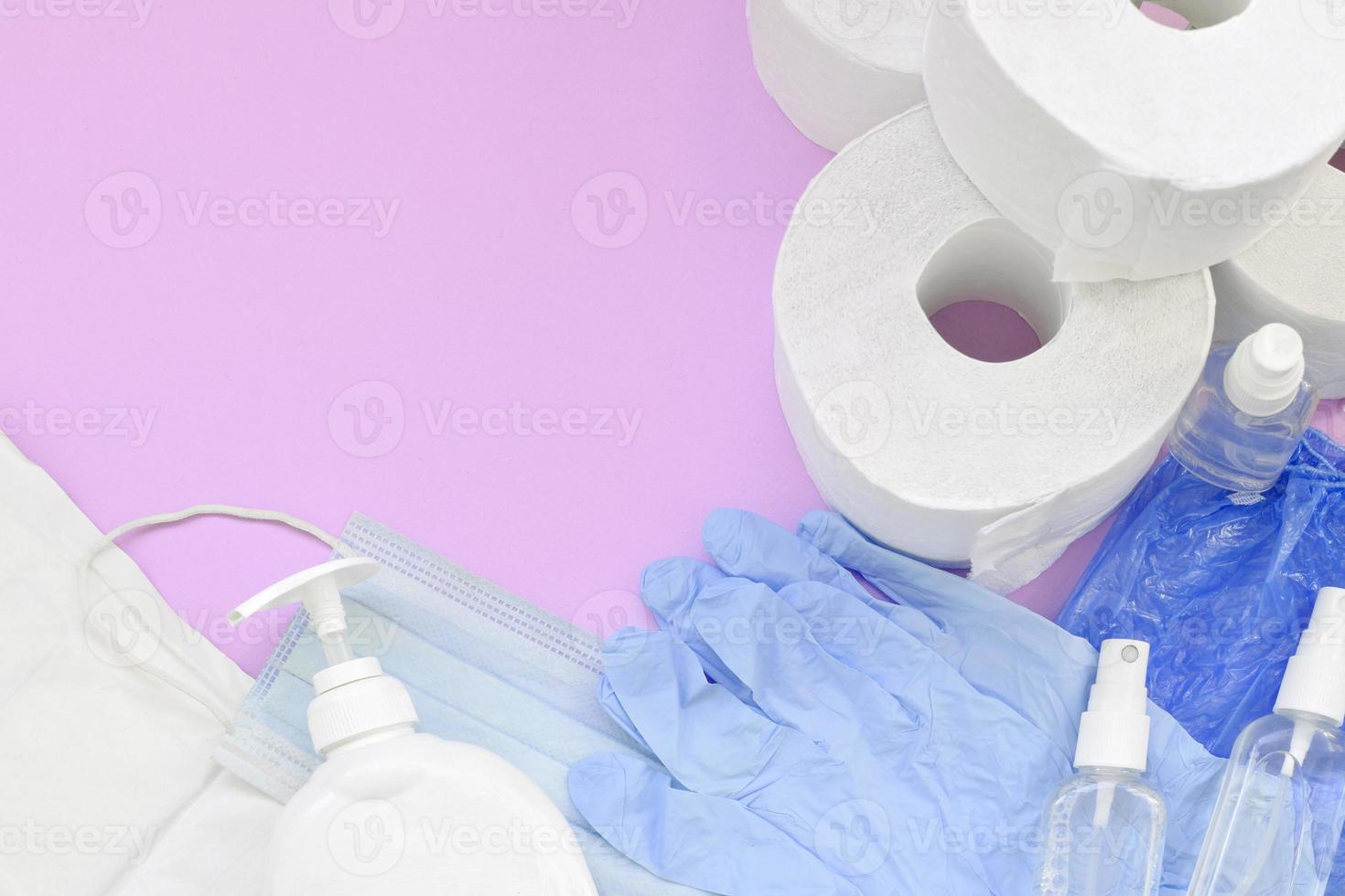 satz wichtiger gegenstände für die covid-19-quarantäne. Toilettenpapier, Einweghandschuhe aus Gummi mit chirurgischer Gesichtsmaske und Händedesinfektionsmittel mit Flüssigseifenflasche auf lila Hintergrund foto
