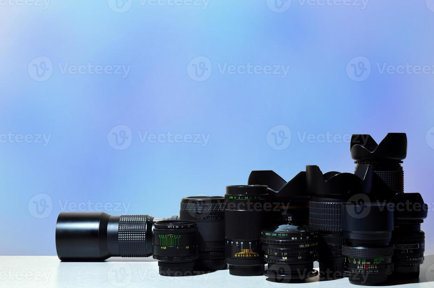 Viele verschiedene professionelle Objektive für Spiegelreflexkameras liegen auf einem farblosen Schreibtisch foto
