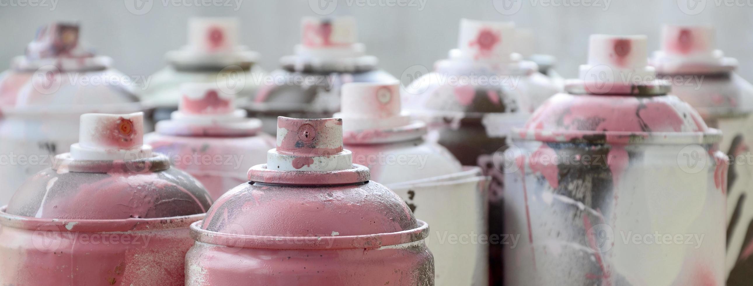 viele schmutzige und gebrauchte Aerosoldosen mit hellrosa Farbe. Makroaufnahme mit geringer Schärfentiefe. selektive Fokussierung auf die Sprühdüse foto