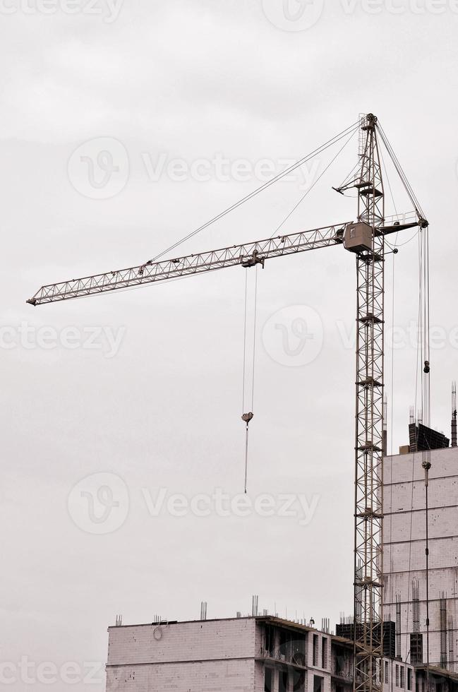 arbeitende hohe Kräne im Inneren mit hohen Gebäuden im Bau vor einem strahlend blauen Himmel. Fortschritt der Kran- und Bauarbeiten. Retro-Ton foto