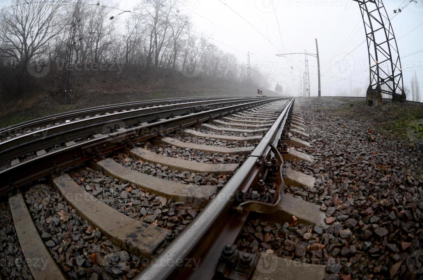 die Bahngleise an einem nebligen Morgen. viele schienen und schwellen gehen in den nebligen horizont. Fisheye-Foto mit erhöhter Verzerrung foto