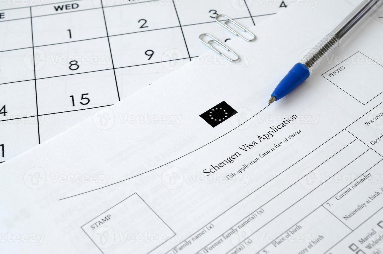 schengen-visumantragsformular und blauer stift auf papierkalenderseite foto