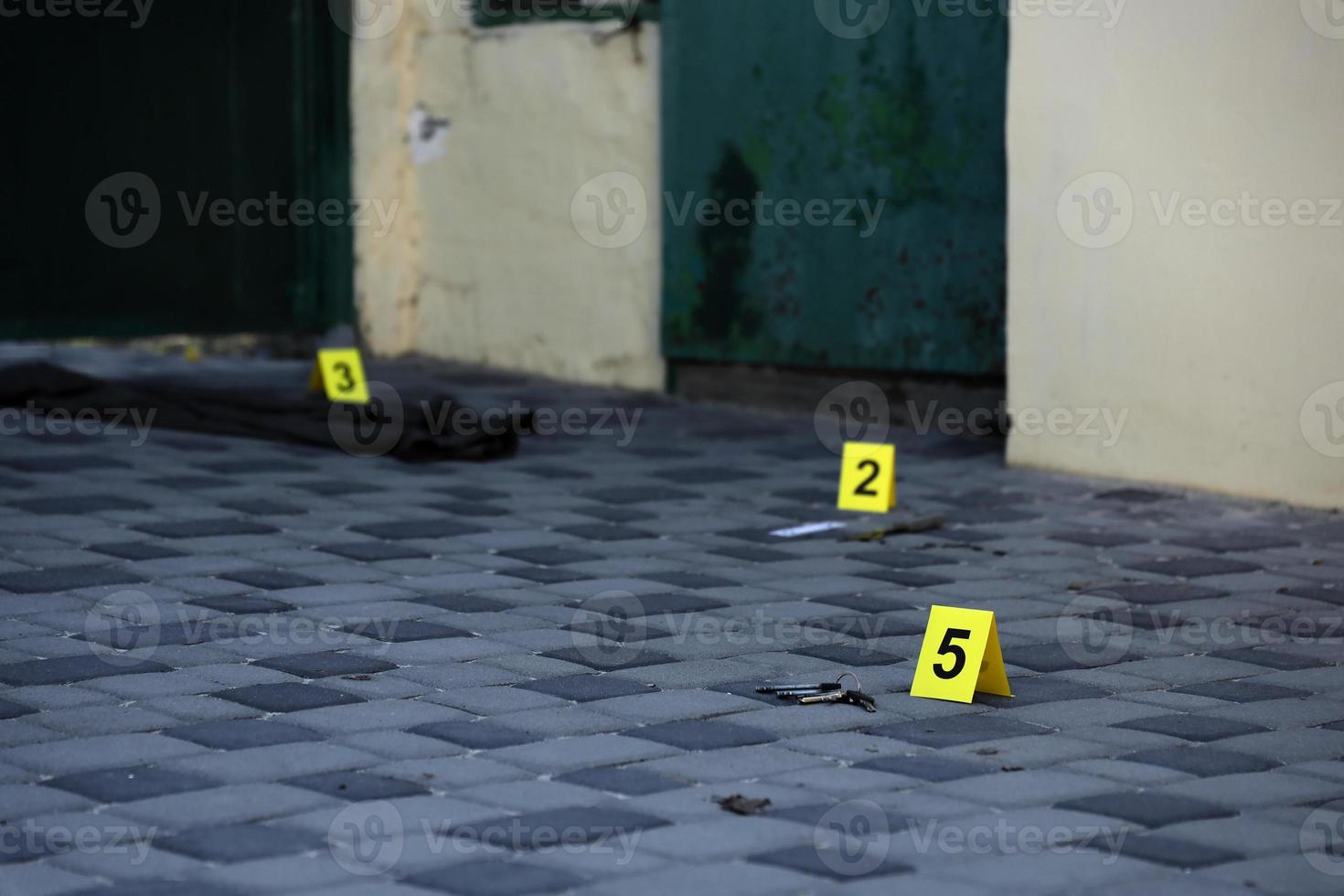 beweis mit gelbem csi-marker zur beweisnummerierung auf dem wohnhinterhof am abend. Tatortuntersuchungskonzept foto