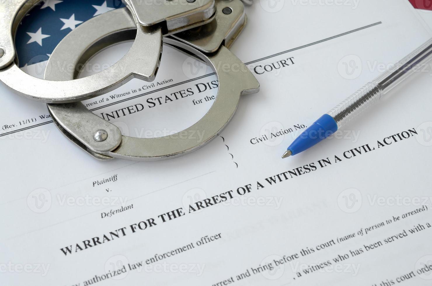 Bezirksgerichtsbefehl für die Festnahme eines Zeugen in einer Zivilklage Papiere mit Handschellen und blauem Stift auf Flagge der Vereinigten Staaten. Erlaubnis, Zeuge der Verhaftung zu sein foto