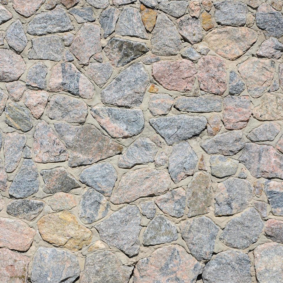 eine graue Steinmauer, zementiert zwischen den abgerundeten Steinen. Hintergrundtextur foto