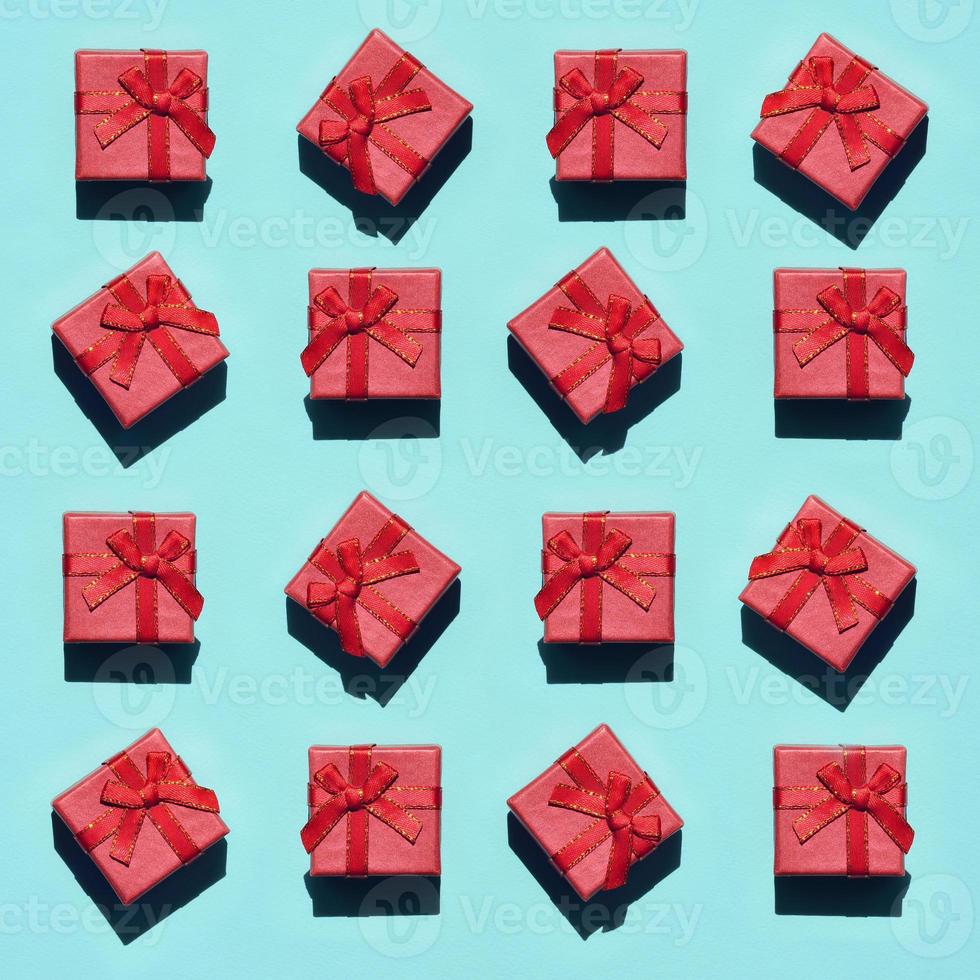 viele kleine rot-rosa geschenkboxen auf texturhintergrund von modischem pastellblauem papier in minimalem konzept. abstraktes Muster foto