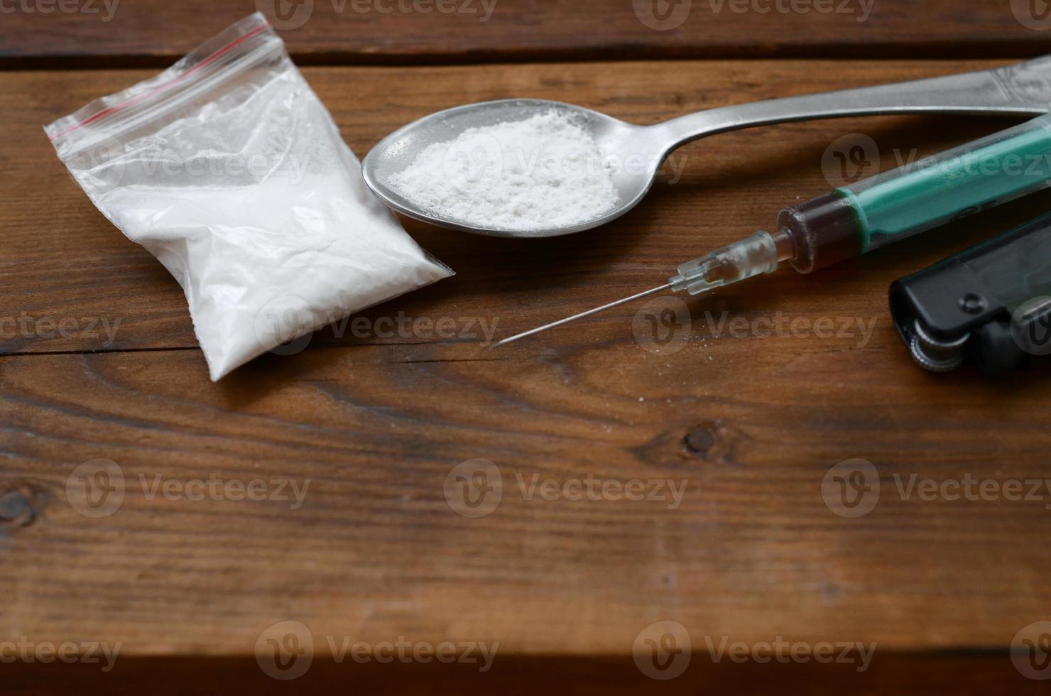 Spritzenfeuerzeug und Löffel voll mit weißem Pulver auf Holzhintergrund. Konzept der Heroin-Drogensucht foto