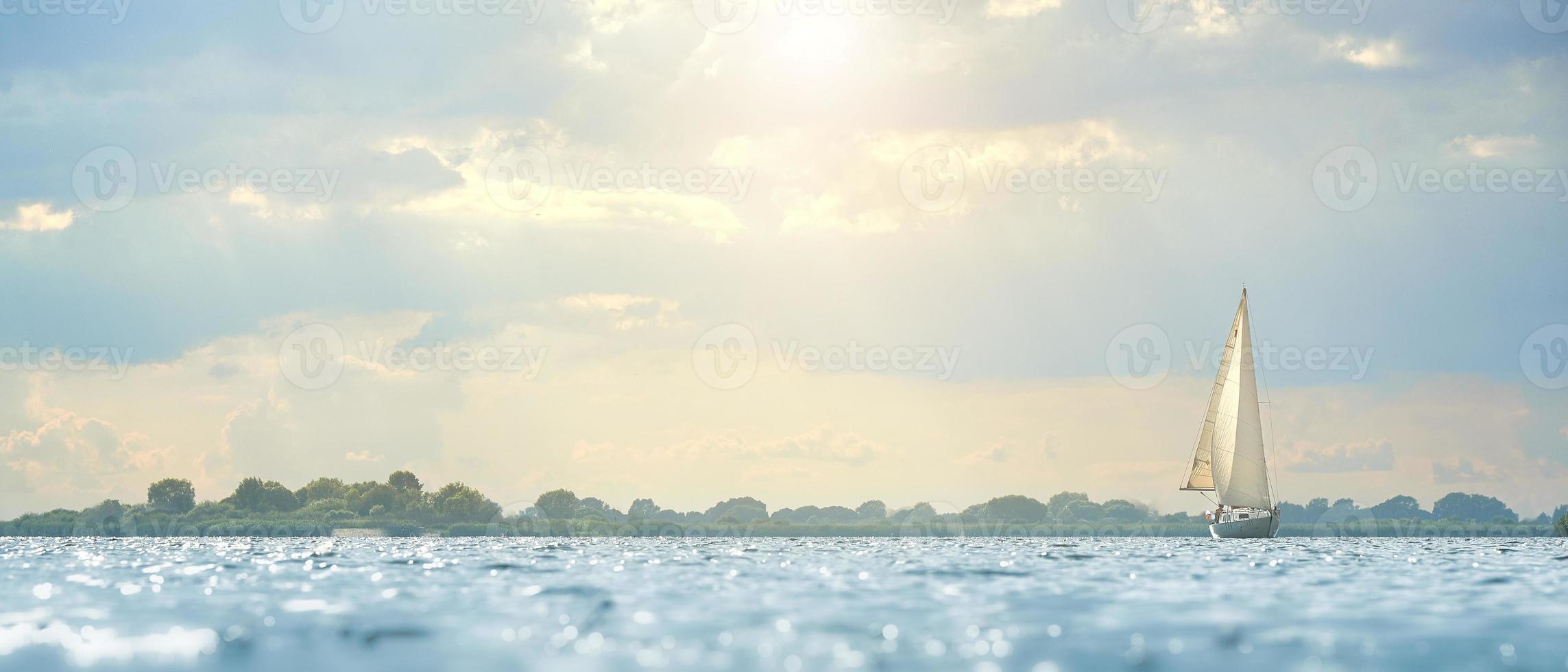 Segeln. Schiffsyachten, die von weichem Sonnenlicht mit Segeln auf dem Fluss beleuchtet werden. foto