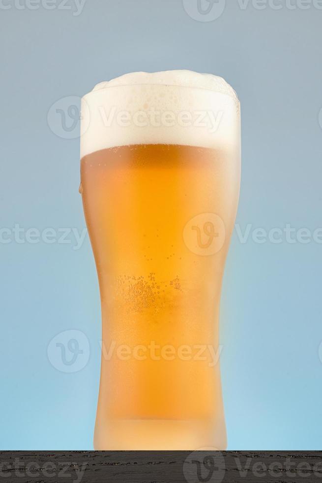 Bierglas Nahaufnahme auf blauem Hintergrund. Nebelglas Bier mit Schaum. foto