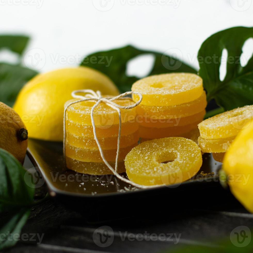 Zitronen-, Orangen- und Grapefruitscheiben in Zucker isoliert auf Holzhintergrund, Nahaufnahme. Marmelade Süßigkeiten. Süßigkeiten mit Zitrusgeschmack. Süßigkeiten foto