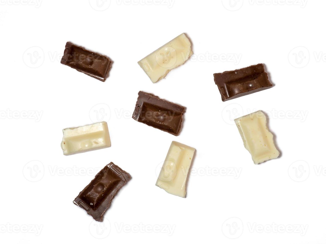 Scheiben von schwarzer und weißer Schokolade auf weißem Hintergrund. verschiedene Pralinen auf dem Tisch. foto