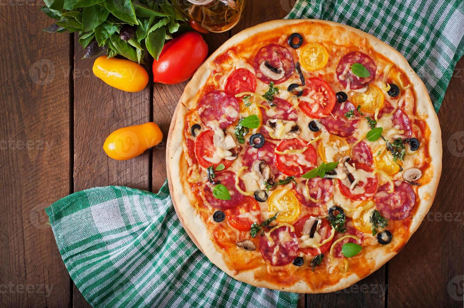 Pizza mit Salami, Tomate, Käse und Oliven foto
