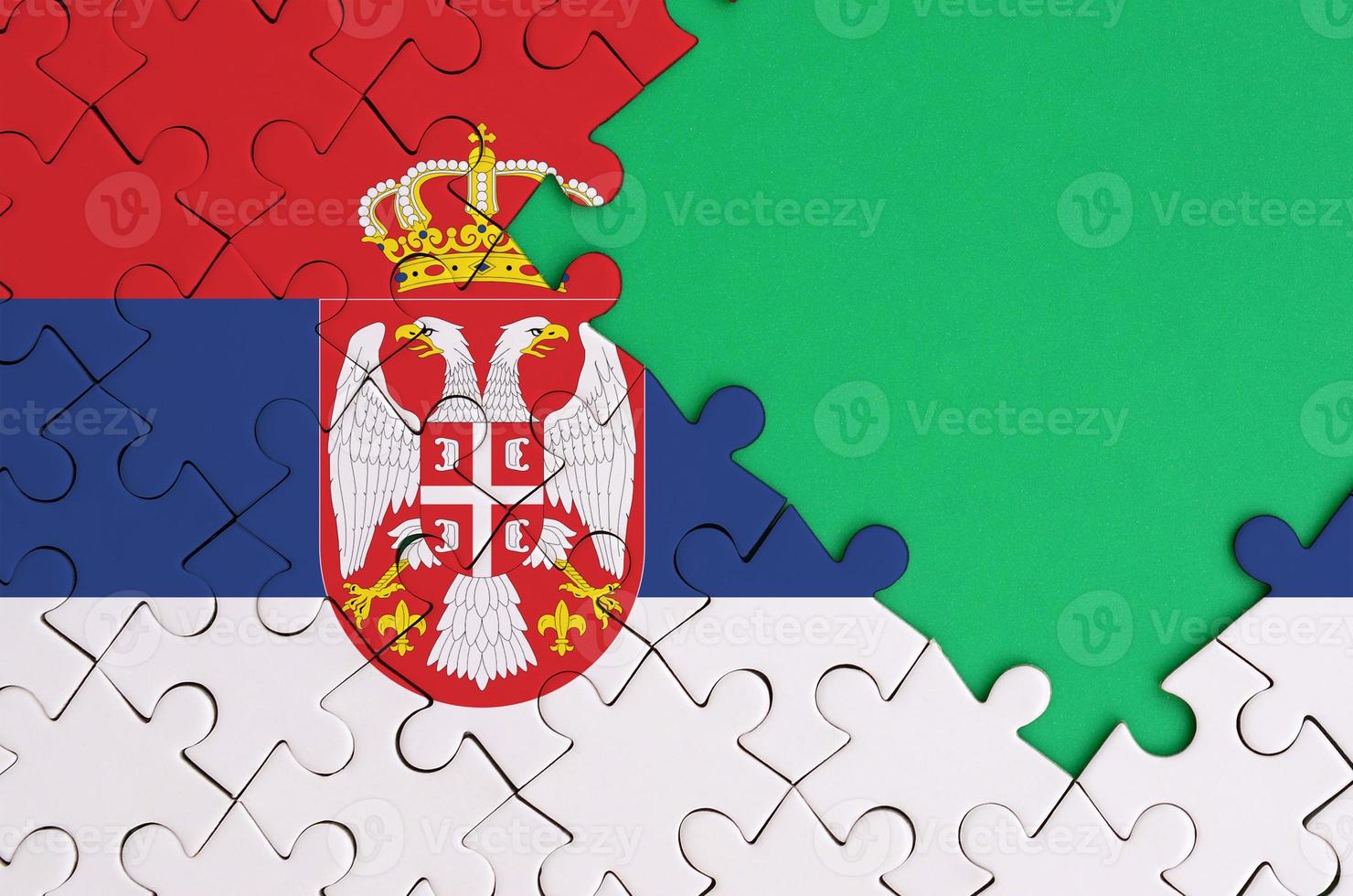 die serbien-flagge ist auf einem fertigen puzzle mit freiem grünem kopierraum auf der rechten seite abgebildet foto